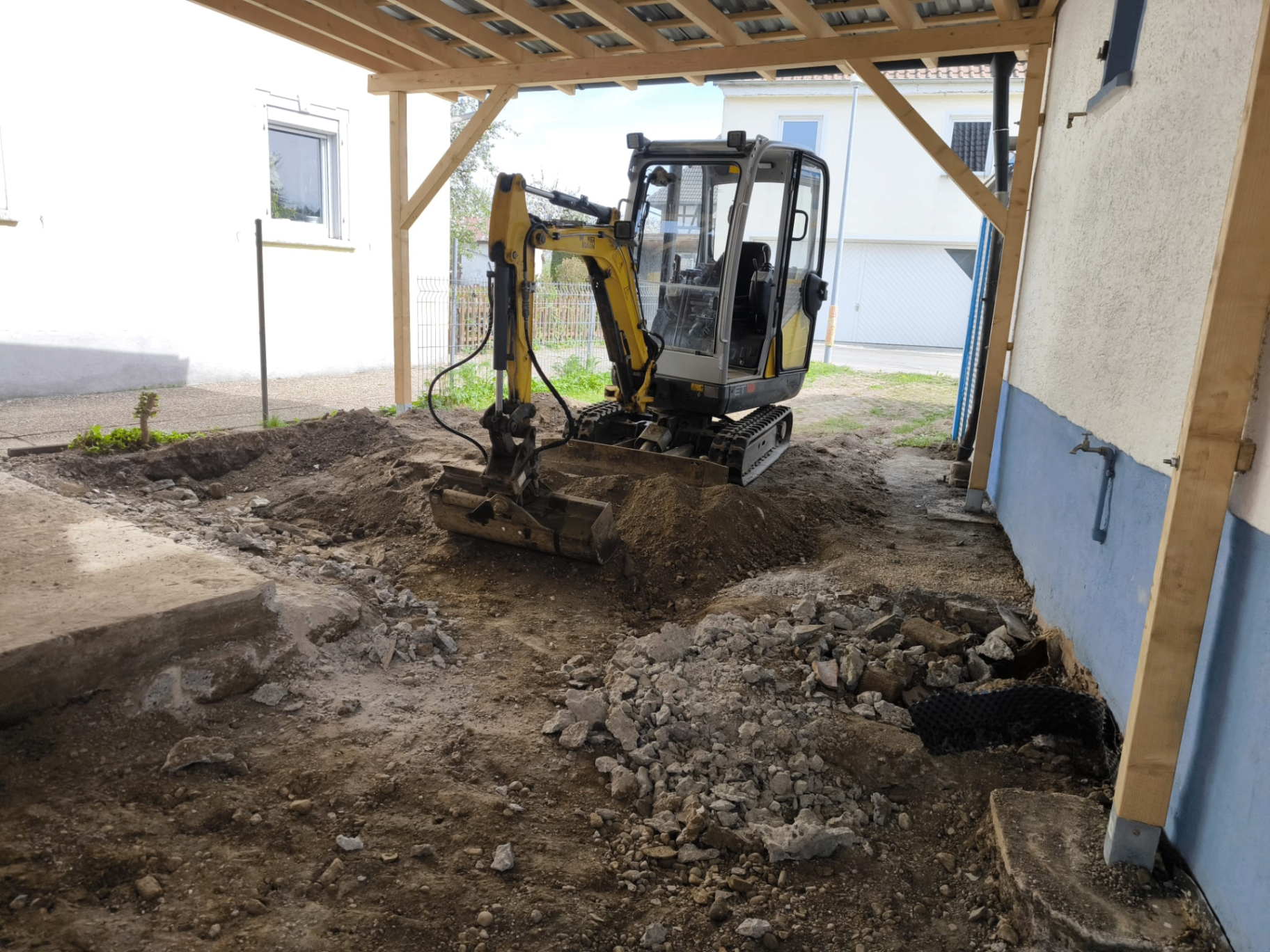 Minibagger im Einsatz unter Carport